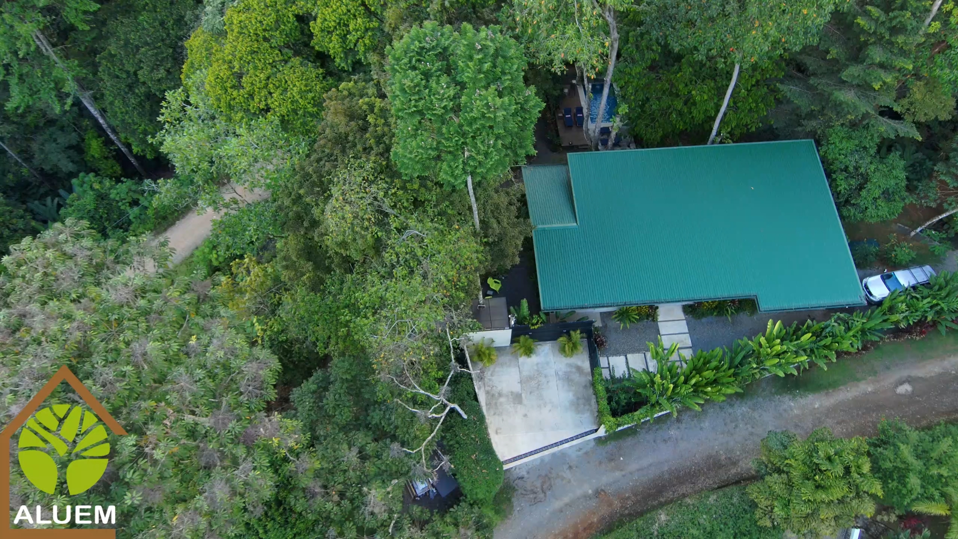 Aerial view of Casa Aluem's green roof, pool, and surrounding rainforest in Uvita